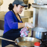 CHEF ROSA Muñoz, who works for Hope & Main member entity Savory Fare, prepares a meal in one of Hope & Main's kitchens. Hope & Main is launching next week its new Nourishing Our Neighbors program to provide free meals to seniors and needy families on the East Bay during the COVID-19 pandemic. / COURTESY RUPERT WHITELEY