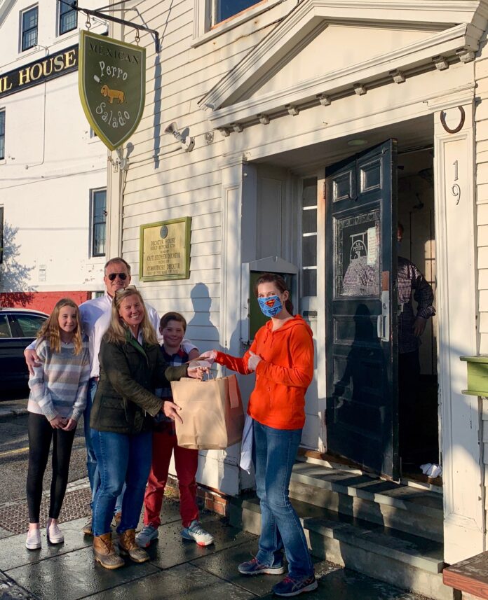 HOGAN ASSOCIATES realtor Caroline Richards, center, picks up a dinner and gift cards from Perro Salado in Newport as part of the agency's 1 MORE HELPING initiative to offer assistance to the community impacted by the COVID-19 pandemic. / COURTESY HOGAN ASSOCIATES