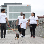 ENROLLED: Torrell Mola, right, has enrolled her children in Providence Promise, a nonprofit focused on providing support for students to seek higher education. From left, Mola’s son Keyon; husband, Bruyere; and daughter Iliyah walk Bella, the family dog, along the Providence Pedestrian Bridge. / PBN PHOTO/ELIZABETH GRAHAM