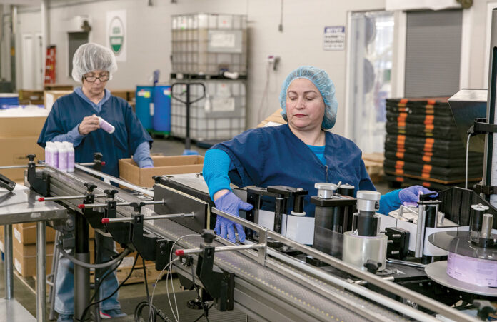 FEELING HEALTHY: Joann Stevens, left, and Angela Uricai help operate a machine at Pure Haven LLC. The Johnston-based company creates beauty products using toxin-free ingredients. / PBN PHOTO/TRACY JENKINS