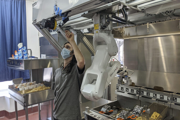 FINE-TUNING: A ­technician makes an adjustment to a robot at Miso Robotics’ White Castle test kitchen in Pasadena, Calif., on July 9. / MISO ROBOTICS VIA AP