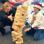GAME DAY: Narragansett Bay Commission Executive Director Laurie Horridge, left, and Liz Kohr enjoy a game of Jenga at a holiday employee appreciation event. / COURTESY NARRAGANSETT BAY COMMISSION