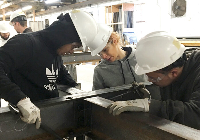 TEAMWORK: Robert Tolson, left, Lisa Silvio and Kyle Brown, right, line up beams to be bolted as part of the ironworking segment of Building Futures’ five-week pre-apprenticeship in 2019. Participants construct a 70-foot-by-14-foot project that contains many of the tools, materials and techniques used in building steel structures.   / COURTESY BUILDING FUTURES 