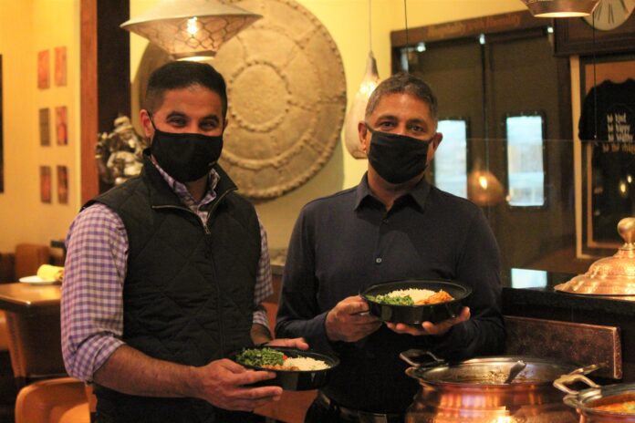 INDIA RESTAURANT in Providence is offering 100 free meals per day throughout December to help people who are impacted by the COVID-19 pandemic. Pictured, from left, are manager Ajay Vinoben and owner Amar Singh. / PBN PHOTO/JAMES BESSETTE