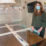 SHIELDED MEAL: Randi Beranbaum, founder and director of Be Collaborative Care in Providence, stands in the dining area at the center where people undergo group therapy for eating disorders. Barriers have been installed at a table so those under treatment can have in-person meals. / PBN PHOTO/MICHAEL SALERNO
