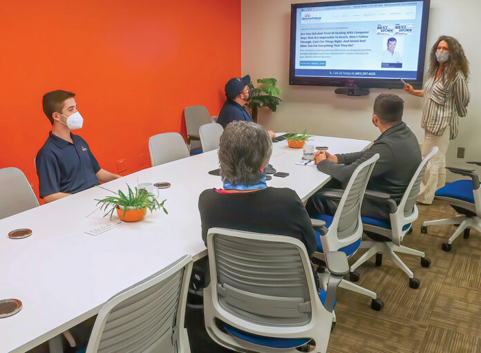 WORKING TOGETHER: Employees at Secure Future Tech Solutions collaborate with one another inside the company’s conference room. / COURTESY SECURE FUTURE TECH SOLUTIONS