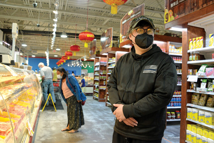 SPECIAL ­FLAVOR: Leo Lin, foreground, is the manager of Good Fortune Supermarket, a Providence grocery store that offers a wide variety of Asian foods. / PBN PHOTO/ELIZABETH GRAHAM
