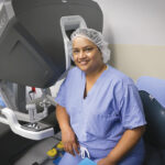 TECH SUPPORT: Dr. Subhashini Ayloo sits with the da Vinci surgery system that helps her perform complex liver surgery. Ayloo joined Brown Surgical Associates in February. / COURTESY LIFESPAN CORP./BILL MURPHY