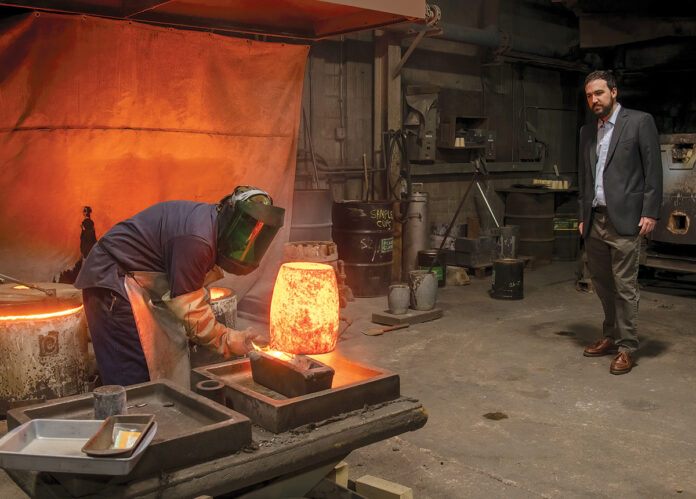 FAMILY MOLD: Francis H. Curren IV, right, vice president of Pease & Curren Inc., a family-owned precious-metal refinement company in Warwick that works with jewelers, pawn brokers, medical offices and recyclers, watches as David Silva, manager/operator, pours molten metal into a mold. / PBN PHOTO/MICHAEL SALERNO