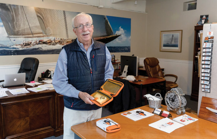 TRAVEL COMPANION: Paul Fleming is the owner of marketing communications firm Fleming and Co. in Newport. The firm also designs and sells products, including the Flight Companion that Fleming is holding, which is a kit he designed for people who travel infrequently and don’t have an established packing routine for carry-on items. / PBN PHOTO/TRACY JENKINS