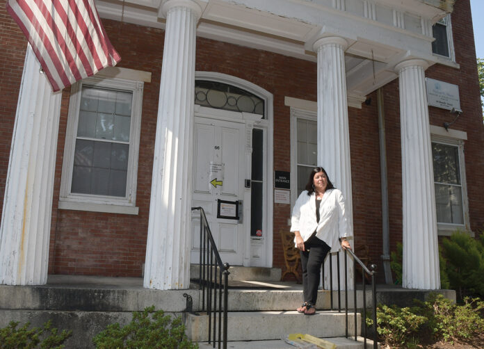 COVID CASUALTY: Stephanie lgoe stands in front of the former Hallworth House building in Providence, a nonprofit nursing home where she served as administrator before it closed in the summer of 2020 due to the COVID-19 pandemic. / PBN PHOTO/MIKE SKORSKI