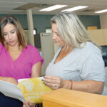 POLICY ­­PERUSAL: Mary Caruso, left, director of business development at Carey, Richmond & Viking Insurance Agency in Middletown, talks with CaraMarie Costa, personal insurance account manager. / PBN PHOTO/ELIZABETH GRAHAM