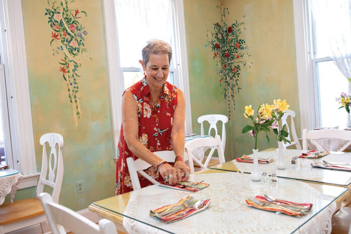 PLACE ­SETTER: Angela Craig prepares the dining room at Newport’s historic Admiral Fitzroy Inn, where she started as the innkeeper in 2004.  / PBN PHOTO/KATE WHITNEY LUCEY