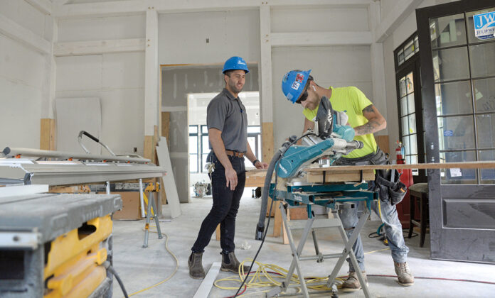 PLENTY OF PROJECTS: Jonathan Yaghjian, left, project manager, and Kurtis Quinn, a carpenter apprentice with Cranston-based Pariseault Builders Inc., work on the Zeta Tau Alpha Sorority House on the University of Rhode Island campus in South Kingstown. While many businesses were forced to close their doors  for much of 2020 due to the COVID-19 pandemic, Pariseault continued to work on a number of multimillion-dollar projects. / PBN PHOTO/ELIZABETH GRAHAM