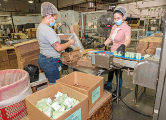 ASSEMBLY LINE: Machine operator Yahalra Santiago, left, helps Hache Diaz pack soap at Bradford Soap Works Inc. in West Warwick. Bradford CEO and President Stuart Benton says the company has had difficulty filling available positions due to a lack of skilled labor in the state. / PBN PHOTO/MICHAEL SALERNO