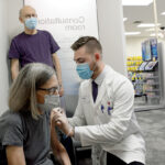 EARLY PROTECTION: Mary Norwalk gets her flu shot from Matt Lefebvre, pharmacy manager at the CVS store on Hope Street in Providence, while Art Norwalk, Mary’s husband, looks on. / PBN PHOTO/ELIZABETH GRAHAM
