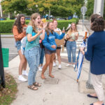 GREETING STUDENTS: Salve Regina University President Kelli J. Armstrong stops to talk with students as they return to campus recently in Newport. Armstrong says she enjoys getting to know students and soon after she arrived at the school in 2019, she implemented “Pizza with the President” gatherings, in which she would invite cohorts of students to her house for pizza. / PBN PHOTO/DAVE HANSEN