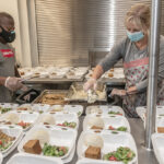 DISHING OUT MEALS: Douglas Spikes, kitchen manager, and volunteer Kathy Block prepare meals for guests at social services nonprofit Amos House in Providence. / PBN PHOTO/MICHAEL SALERNO