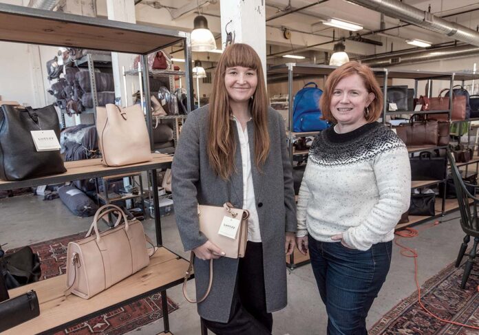FASHION ON DISPLAY: Leather bags and suitcases surround former Lotuff Leather executives Lindy McDonough, left, and Ellen McNulty-Brown in this photo taken in 2016. / PBN FILE PHOTO/MICHAEL SALERNO