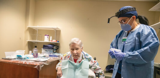 CRUCIAL CHECKUP: Margaret Vargas, right, a dental hygienist with nonprofit CareLink Inc.’s mobile dental clinic, conducts an examination of Sister Anne Kelly at The Villa at Saint Antoine in North Smithfield. The clinic serves 3,000 patients at 53 Rhode Island nursing homes.  / PBN PHOTO/MICHAEL SALERNO