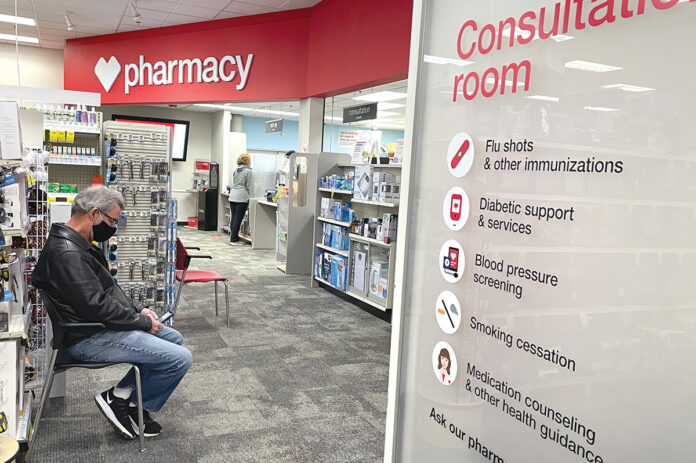 PREP TIME: A man waits to receive a COVID-19 vaccine at a CVS pharmacy store in Buffalo Grove, Ill., earlier this month. The Woonsocket-based chain has plans to put emphasis on primary care at some locations.  / AP PHOTO/NAM Y. HUH