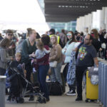 TRAVELERS LINE UP at the Southwest Airlines curbside check-in area at Denver International on Sunday. Airlines canceled hundreds of flights Sunday, citing staffing problems tied to COVID-19 to extend the nation's travel problems beyond Christmas. AP PHOTO/DAVID ZALUBOWSKI