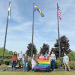 PROUD DISPLAY: Amgen Inc. employees hold the progress pride flag, a variant of the pride flag, or the rainbow flag, a symbol of lesbian, gay, bisexual, transgender and queer pride, which flies overhead on the center flag pole at the company’s West Greenwich campus.  COURTESY AMGEN INC.