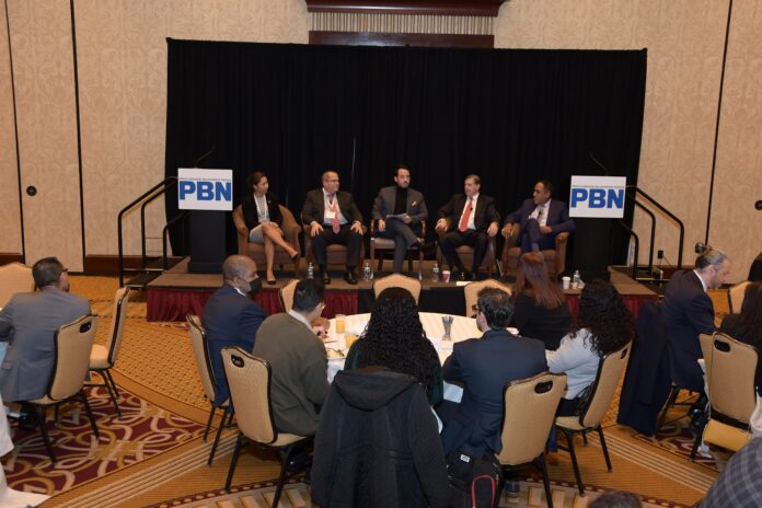 KEVIN MATTA, center of the stage, head of diversity and inclusion for Thielsch Engineering Inc., leads the discussion among panelists at Providence Business News' 2021 Diversity & Inclusion Summit and Award program at Crowne Plaza Providence-Warwick on Thursday. The other panel members are, from left, Dorca M. Paulino, diversity director for the R.I. Judiciary; Peter Rodriquez, executive director/plant manager for Amgen Rhode Island in West Greenwich; Neil D. Steinberg, CEO and president of the Rhode Island Foundation; and Lawrence E. Wilson, managing director at The Wilson Organization. PBN PHOTO/MIKE SKORSKI