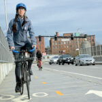 FITTING IN: Liza Burkin, organizer for the Providence Streets Coalition, uses new bike lanes on the Clifford Street bridge in Providence. The new lanes are part of Mayor Jorge O. Elorza’s hotly debated Great Streets Initiative to connect the city’s neighborhoods through bike lanes.  / PBN FILE PHOTO/ELIZABETH GRAHAM