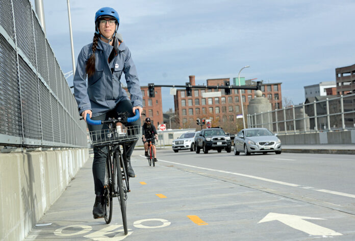 FITTING IN: Liza Burkin, organizer for the Providence Streets Coalition, uses new bike lanes on the Clifford Street bridge in Providence. The new lanes are part of Mayor Jorge O. Elorza’s hotly debated Great Streets Initiative to connect the city’s neighborhoods through bike lanes.  / PBN FILE PHOTO/ELIZABETH GRAHAM