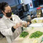 FRESH ­INGREDIENTS: Master chef Rosa Munoz, of Savory Fare, prepares a home-cooked meal in the commercial kitchen at food incubator Hope & Main in ­Warren. / PBN PHOTO/MICHAEL SALERNO