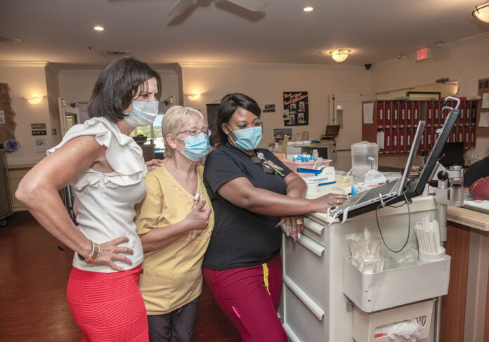 ON DUTY: From left, Kathleen Gerber, executive director at Cherry Hill Manor Nursing & Rehabilitation in Johnston; Donna LaBonte, a certified nursing assistant; and Dorothy Bishop, a medical technician, check computer records at the nursing home. Cherry Hill and most other Rhode Island nursing homes are struggling through financial difficulties made worse by a severe labor shortage.  PBN PHOTO/MICHAEL SALERNO