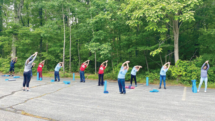 LIMBERING UP: Employees at Groov-Pin Corp. in Smithfield stretch before an outdoor yoga session, one of several initiatives the company introduced that became popular and is now a monthly event. COURTESY GROOV-PIN CORP.