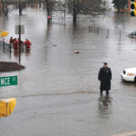 DANGER AHEAD? A police officer directs traffic away from River Street in West Warwick during widespread flooding in April 2010 while firefighters evacuate residents. Following flood insurance rate changes in October, about 10% of homeowners in the state have dropped their coverage.  PBN FILE PHOTO
