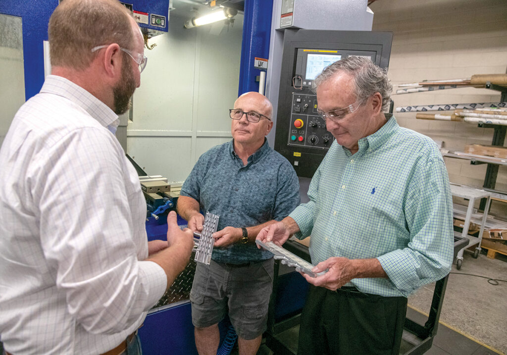 PRODUCT REVIEW: Jade Manufacturing Co. Vice President Chris Burch, left, Director of Manufacturing Steve Gruner, center, and President Don Boyle examine some trays they produced on their milling machine.  PBN PHOTO/MICHAEL SALERNO
