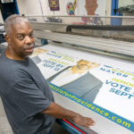 SIGN OF THE TIMES: Gary Wallace is the owner of Hall of GraFX, a printing shop in Providence that has produced campaign materials for candidates, such as this banner for Gonzalo Cuervo, who finished second in the Providence mayoral primary on Sept. 13. PBN PHOTO/ MICHAEL SALERNO