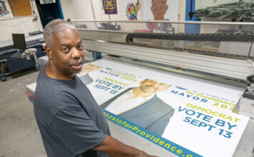 SIGN OF THE TIMES: Gary Wallace is the owner of Hall of GraFX, a printing shop in Providence that has produced campaign materials for candidates, such as this banner for Gonzalo Cuervo, who finished second in the Providence mayoral primary on Sept. 13. PBN PHOTO/ MICHAEL SALERNO