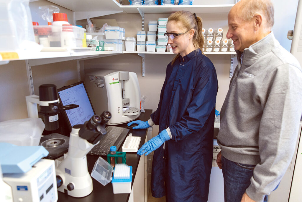 SEEKING APPROVAL: Neurotech Pharmaceuticals Inc. CEO Richard Small, right, speaks with process development engineer Lovisa Selander in the biotech company’s lab in Cumberland. Neurotech is completing final trials for an implantable device to treat eye disease, but Small says several economic factors have proved challenging recently.  PBN PHOTO/ RUPERT WHITELEY