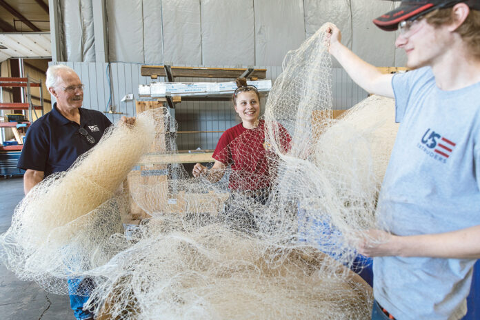 NOTHING BUT NET: From left, U.S. Extruders Inc. Plant Manager Wade Lippo and assemblers Lexus Falcone and Dan Brownhead work with fishing net.  PBN PHOTO/RUPERT WHITELEY