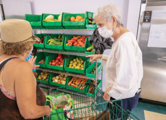 HELPING HAND: Dr. Martin Luther King Jr. Community Center volunteer Susan Barnes, right, assists a customer in the nonprofit organization’s food pantry in Newport. PBN PHOTO/DAVID HANSEN