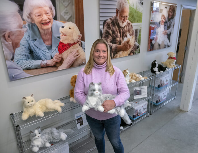 NEW BREED OF COMPANIONSHIP: Meghan Gamboa, Ageless Innovation LLC co-founder and senior vice president, holds an animatronic cat at the company’s Pawtucket headquarters. The cats, dogs and birds produced by Ageless Innovation have been shown to be beneficial for the mental health of the elderly. PBN PHOTO/ MICHAEL SALERNO