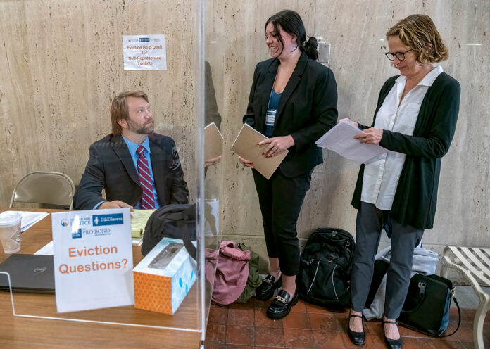LEGAL  ASSISTANCE: Rhode Island Legal Services staff attorney Brian Furgal, Roger Williams University School of Law student Nicole Palmer, center, and RWU faculty member Eliza Vorengerg operate the Eviction Help Desk outside Sixth District Court at the Garrahy Judicial Complex in Providence. PBN PHOTO/ MICHAEL SALERNO