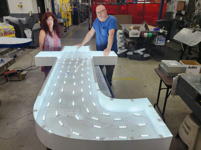 ON TARGET: Natalia ­Pelletier, Poyant Signs Inc.’s senior project manager, and Bill Furey, the company’s channel letter production lead, stand over a sign made for Target.  COURTESY POYANT SIGNS INC.