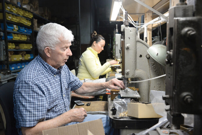 STAMP OF APPROVAL: Snow Findings Co. President Bob Snow and employee Maria Pena work on the metal stamping service company’s manufacturing floor  in West Warwick. PBN PHOTO/ ELIZABETH GRAHAM