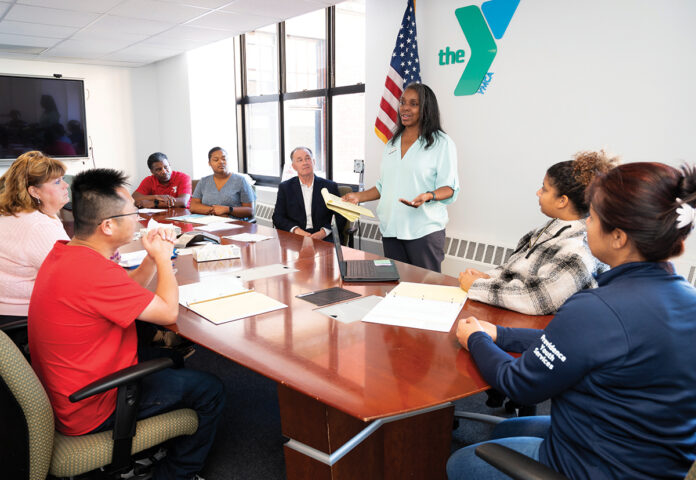 UNITED: YMCA of Greater Providence Assistant Director of Diversity, Equity and Inclusion Kira Wills, standing, addresses her colleagues at the organization’s Providence office. Wills says the YMCA is for all, which is reflected by its staff being comprised of individuals who are neurodivergent, have disabilities, speak multiple languages, identify as LGBTQIA and are different ages. PBN PHOTO/DAVID HANSEN