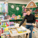 SETTING UP: Rachel Lawler, a volunteer at the Martin Luther King Jr. Community Center in Newport, organizes toys for the organization’s “­Santa’s Workshop” program, which allows families to choose from a selection of free gifts for their children. PBN PHOTO/DAVID HANSEN