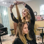 GOING UP: Michelle Murphy, owner of Roots Hair Salon LLC in Cranston, works on Talias Oakane of ­Cranston. Murphy says she may have to raise the rent she charges her stylists, who recently raised their prices due to the increased cost of products, because her monthly payment to rent the building space for the salon recently increased. PBN PHOTO/MICHAEL SALERNO