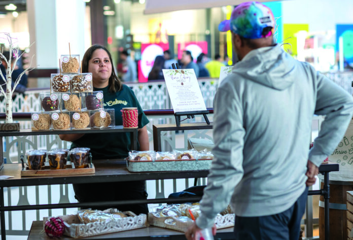 POP-UP BAKERY: Thrive Cakery LLC owner Jasmine Mendez speaks with John Shaw of Cumberland about her products, which she will be offering through a pop-up kiosk on the second floor of the Providence Place mall through the new year. PBN PHOTO/MICHAEL SALERNO