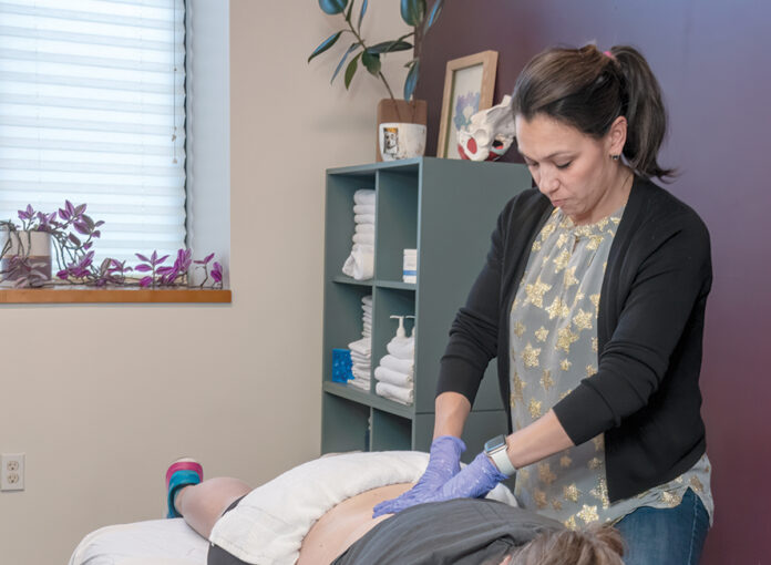 HEALING HANDS: Amy E. Smith, one of the two owners of Roots Specialty Services LLC in Providence, a studio offering physical therapy, yoga and massage services, works on Shariah Landry from Cranston. PBN PHOTO/MICHAEL SALERNO