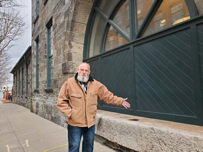NEIGHBORHOOD PRIDE: Olin Thompson, a ­Jewelry District resident and amateur historian, points to the architectural features on a stone building at 110 Elm St. that was once a foundry and is now leased by Brown University for administrative and medical offices.  PBN PHOTO/CLAUDIA CHIAPPA